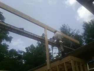 Carpenter setting a ridge beam over a new addition frame — Ice Dam Removal by Roofing Brothers in Shedd