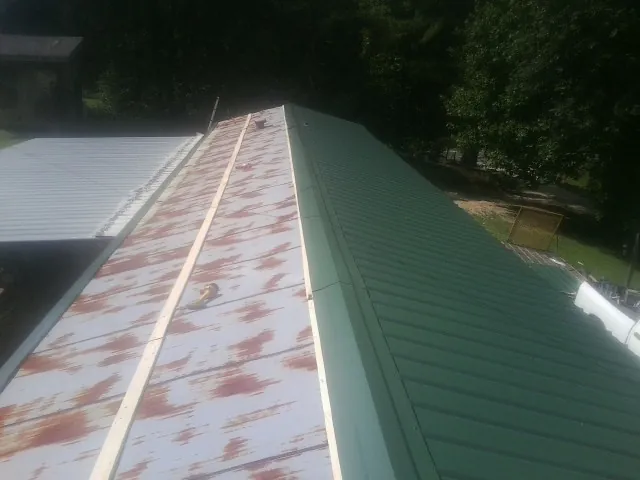 Old rusted panels beside newly installed green metal roofing — Wind Damage Roof Repair by Roofing Brothers in Shedd