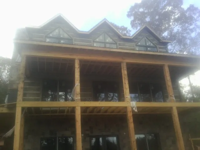 Dormers and porch framing on a large log home under construction — Roof Coating work by our crew in Shedd