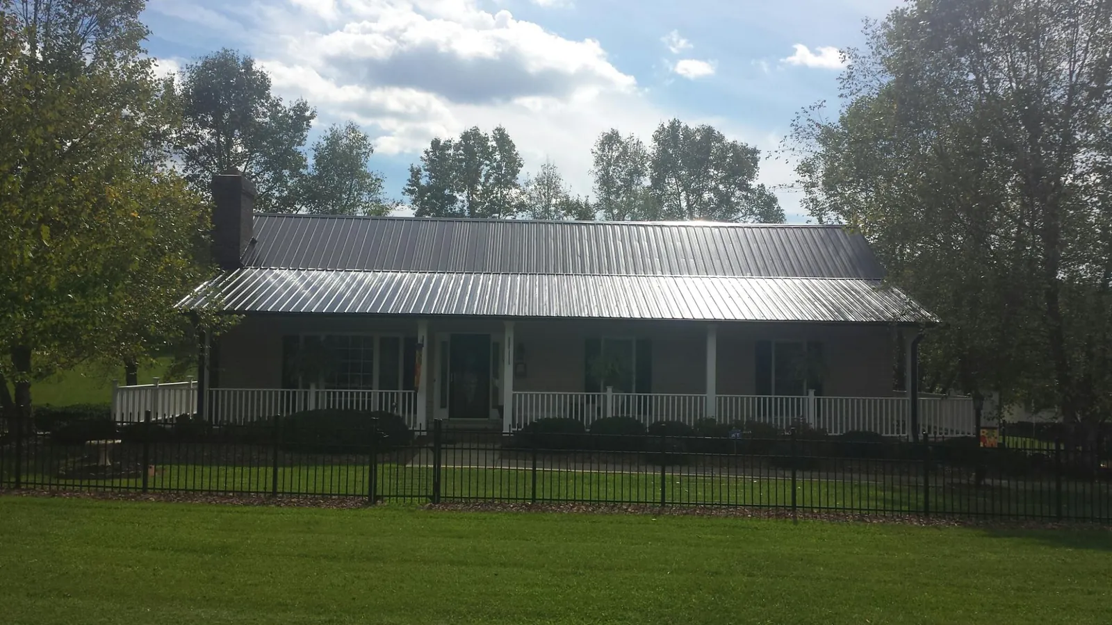Gray metal roof on a brick ranch with a full width front porch — Gutter Guard Installation work by our crew in Shedd