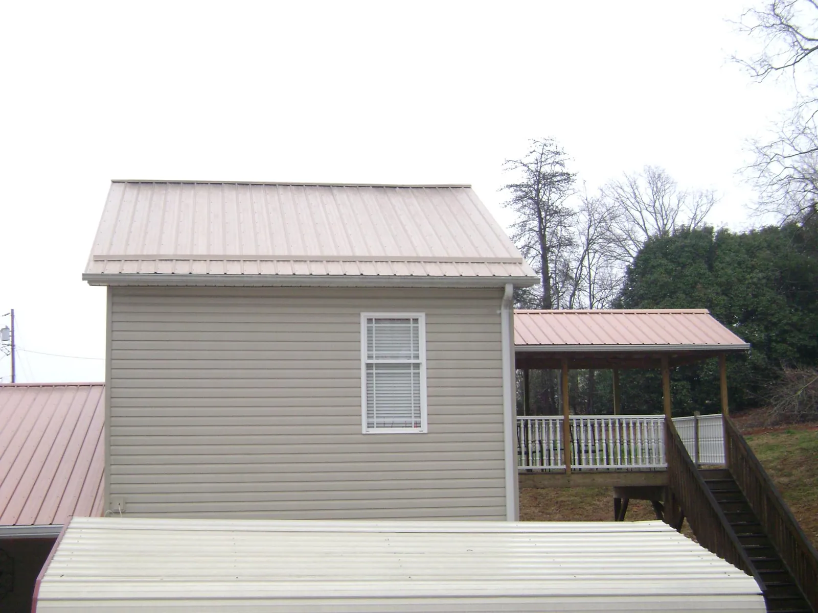 Tan metal roofs on a two story addition and attached porch, from a Roof Replacement job in Shedd
