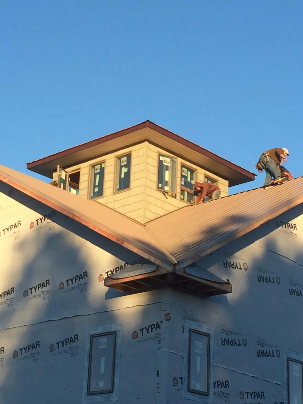 Roofers working around a rooftop cupola on a new metal roof at sunset — Roof Waterproofing in Shedd by Roofing Brothers